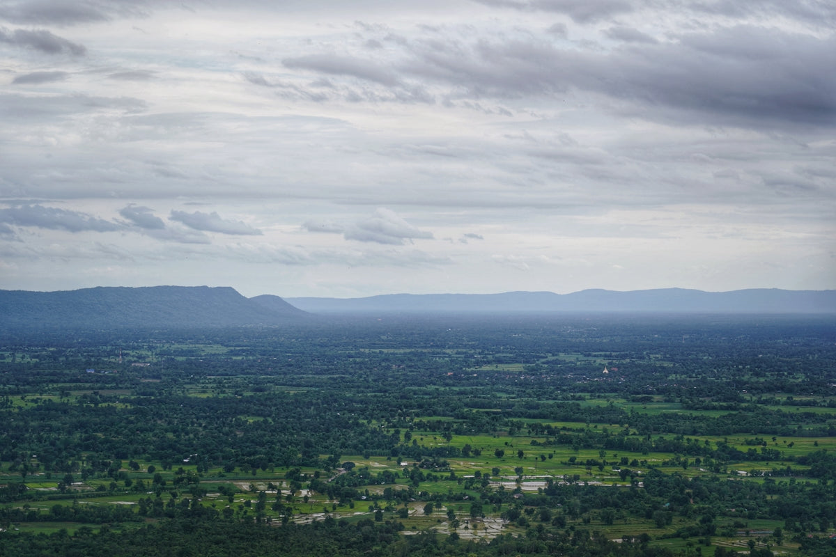 green trees and mountains under white clouds during daytime
