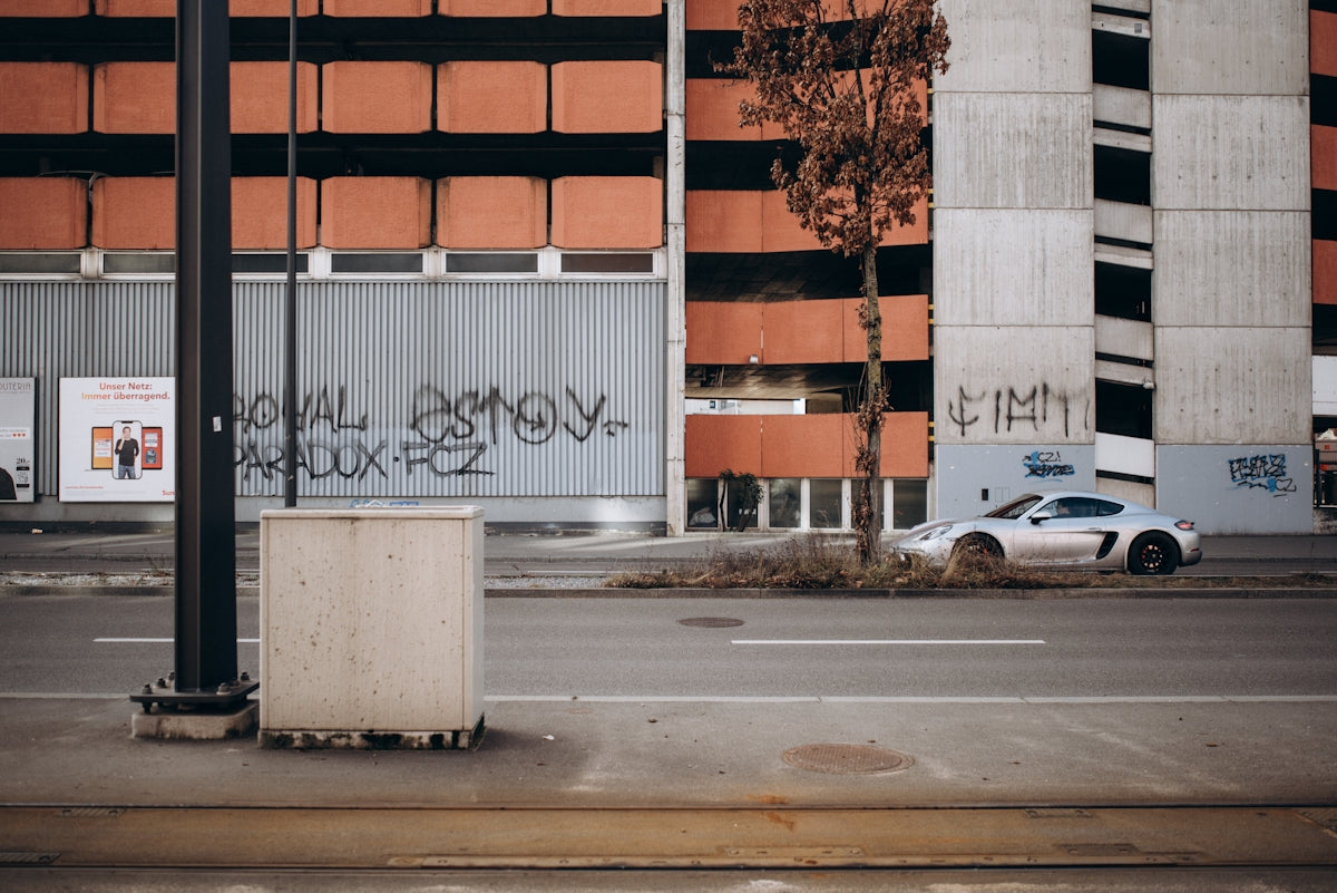 a car parked on the side of a road next to a tall building
