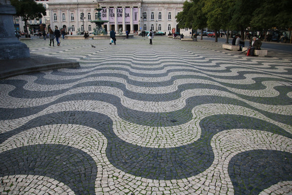 a cobblestone street with a large building in the background