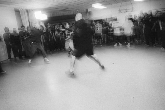 a group of people watching a man kick a soccer ball