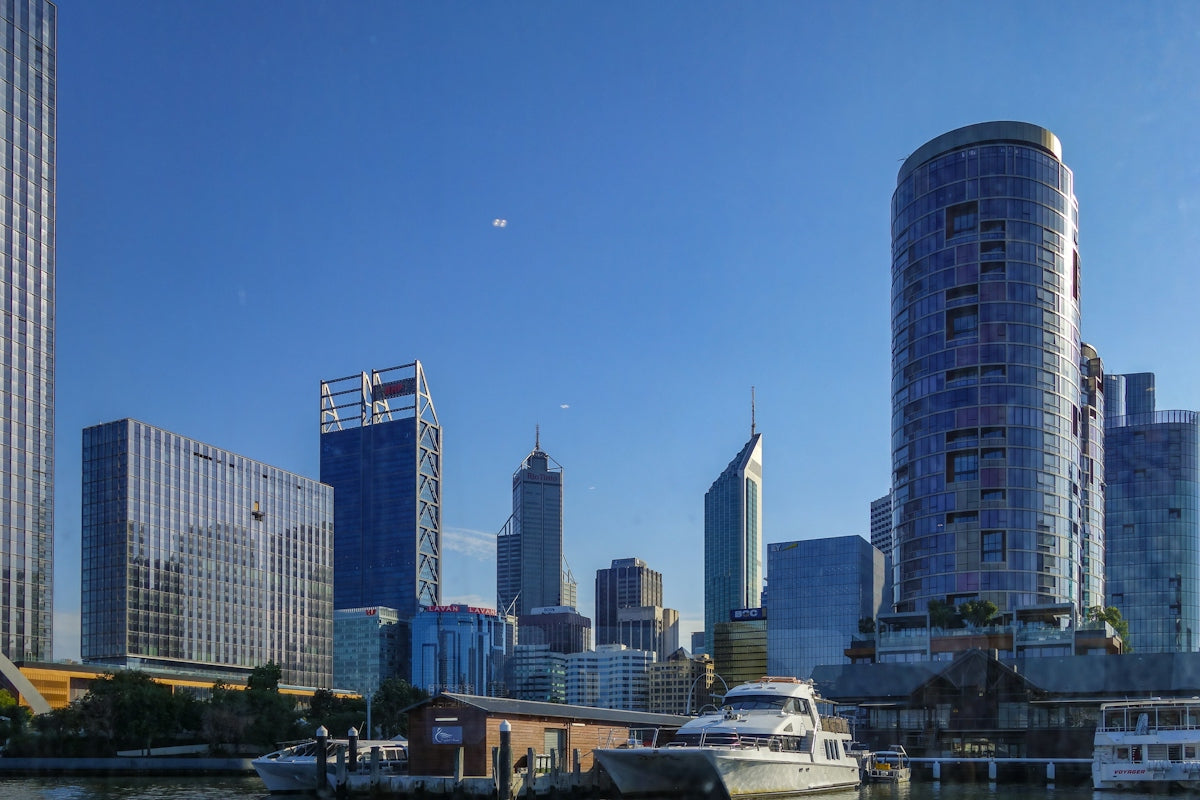 Modern cityscape with skyscrapers and boats under a blue sky