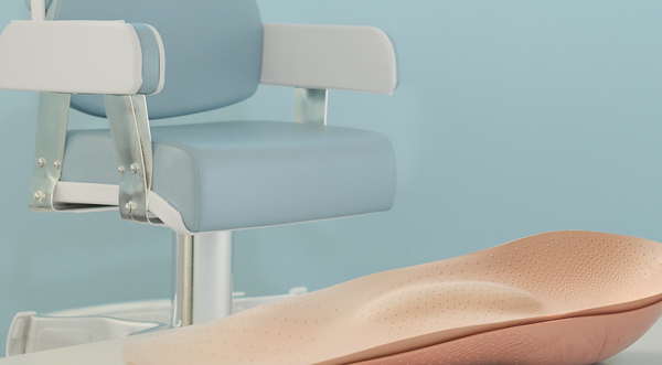 Illustrative photograph of a foot-support insole beside a podiatry chair