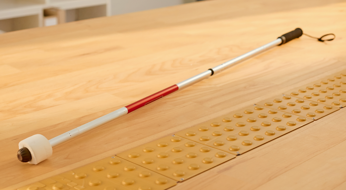 Illustrative photograph of a child-sized mobility cane and tactile learning strip