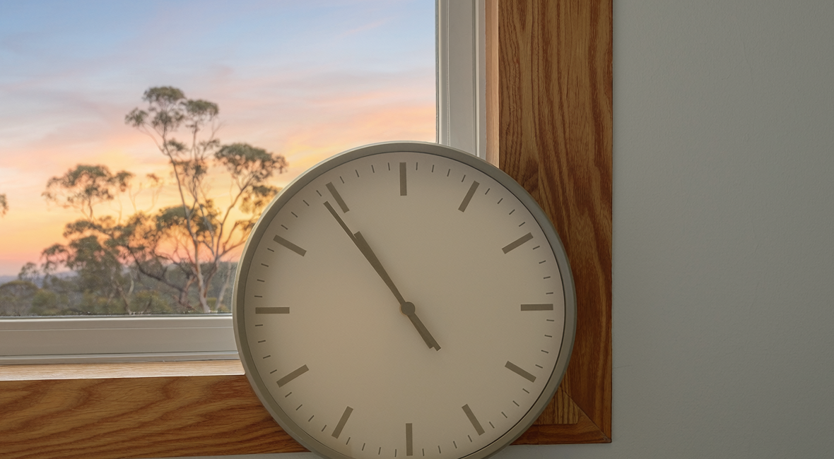 A clock by a window in evening light