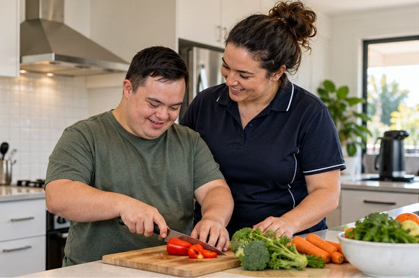 Support worker and participant practising everyday meal preparation in a bright home