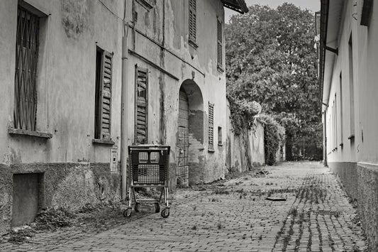 grayscale photo of a shopping cart in the middle of a brick wall