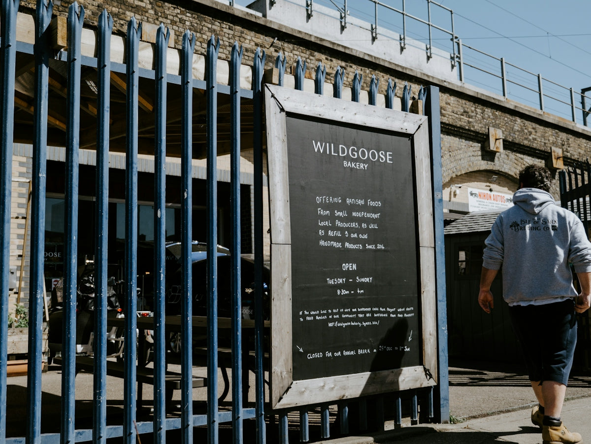 man in gray t-shirt standing beside blue metal fence during daytime