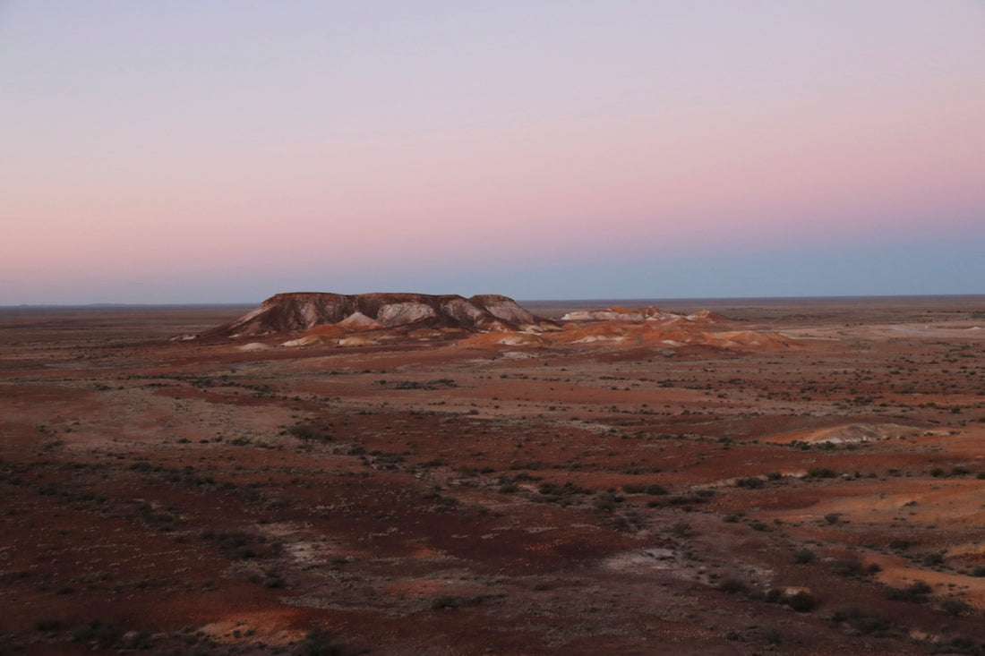 a desert landscape with a hill in the distance