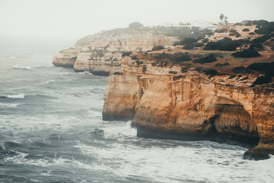 a rocky cliff overlooks the ocean on a foggy day