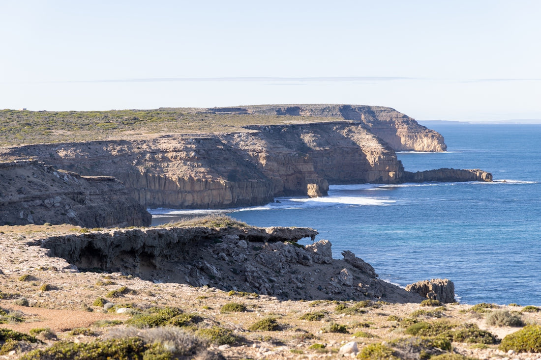 a large body of water sitting next to a rocky cliff