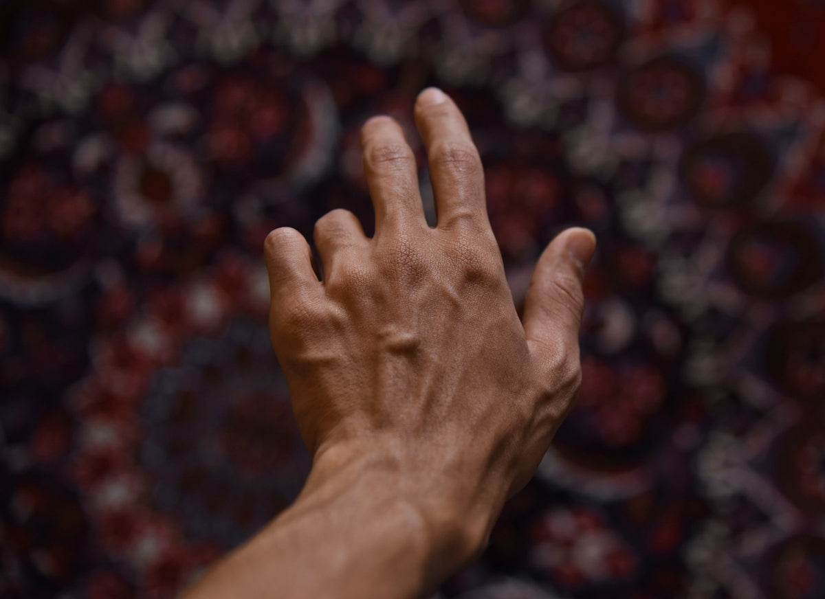 A hand reaches out against a patterned background.