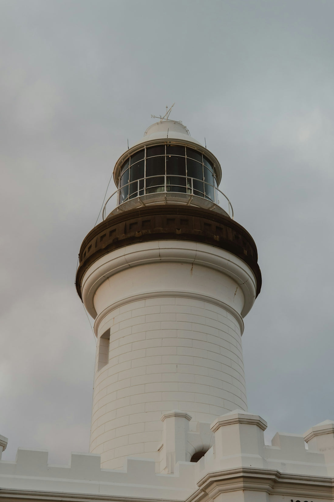 White lighthouse stands tall against a cloudy sky.