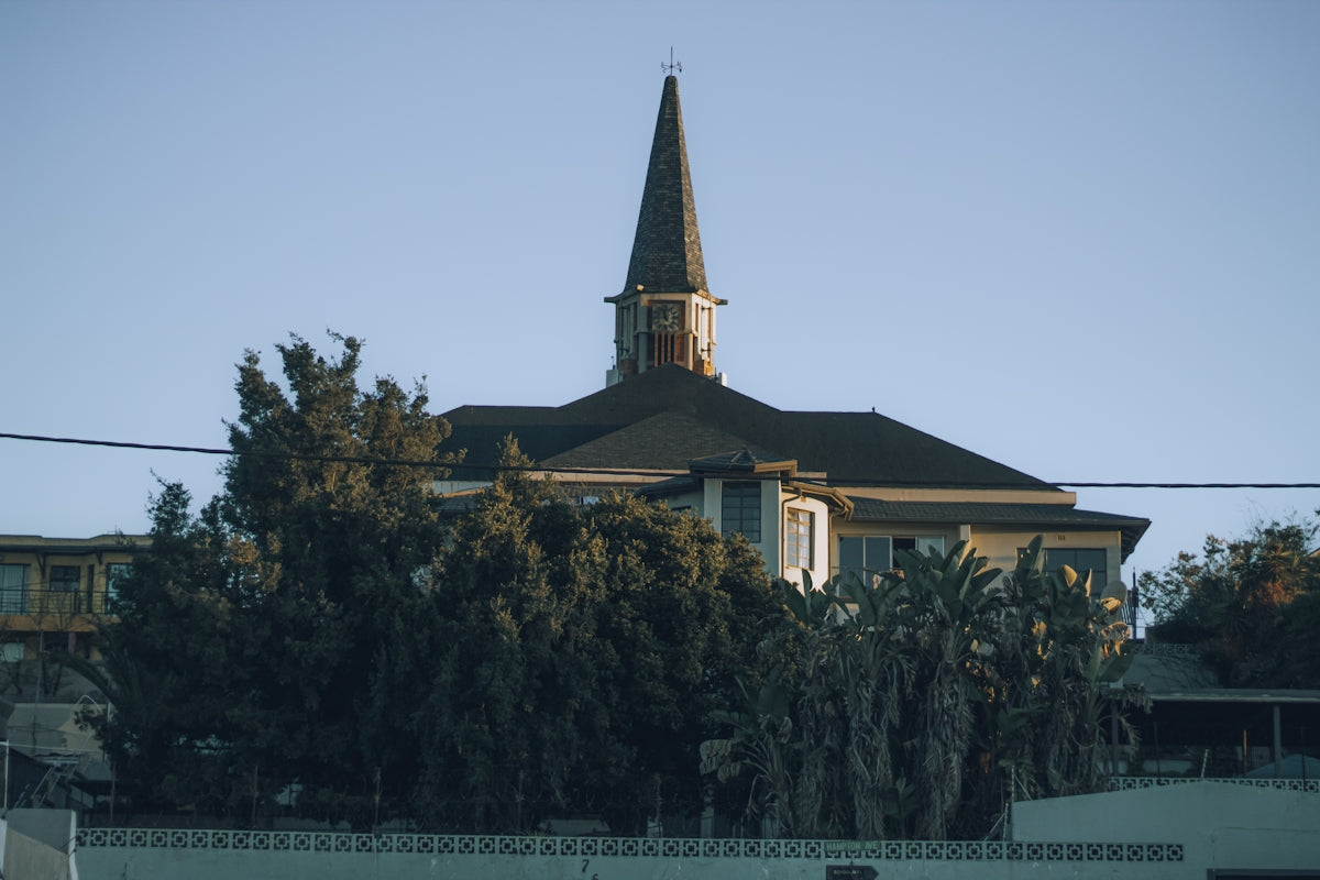 A church with a tall steeple stands against the blue sky