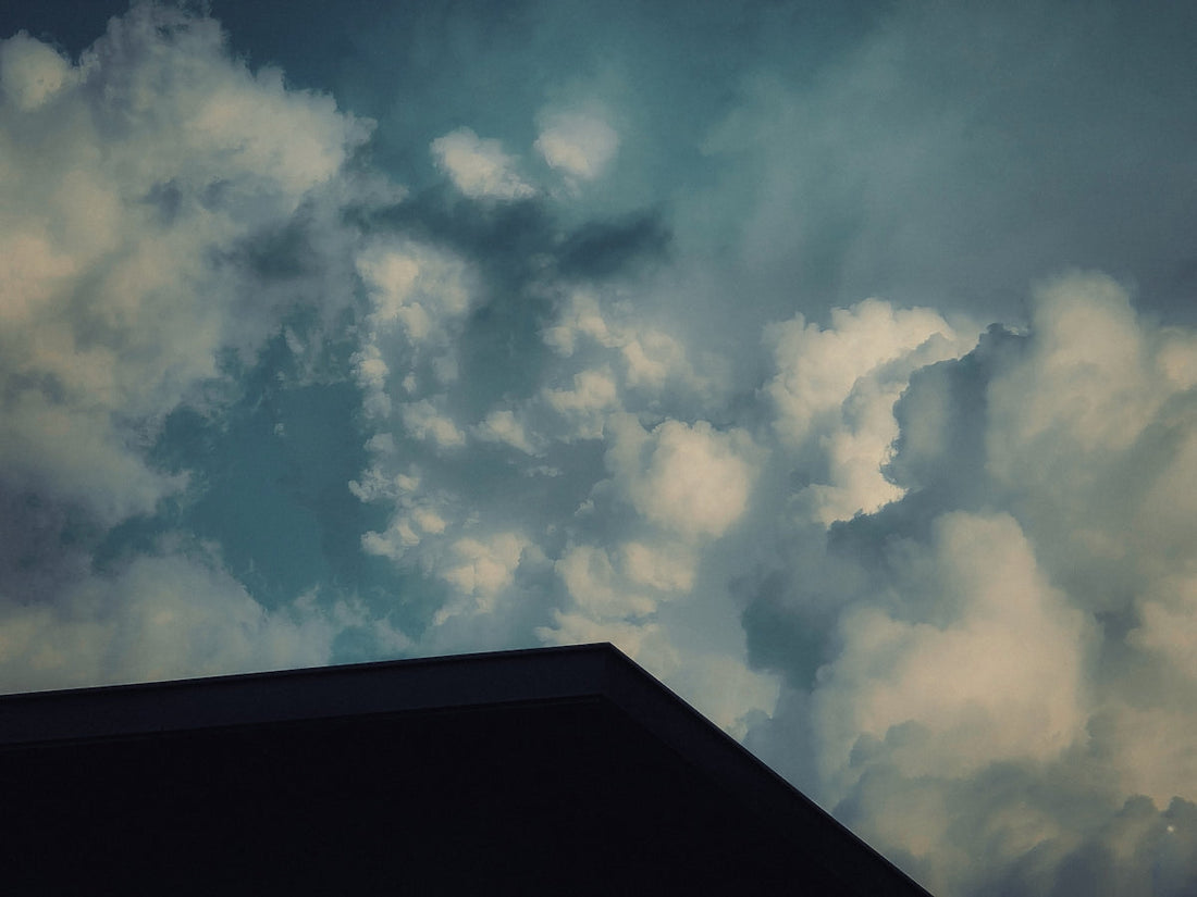 Overcast, cloudy sky with a building's roof.