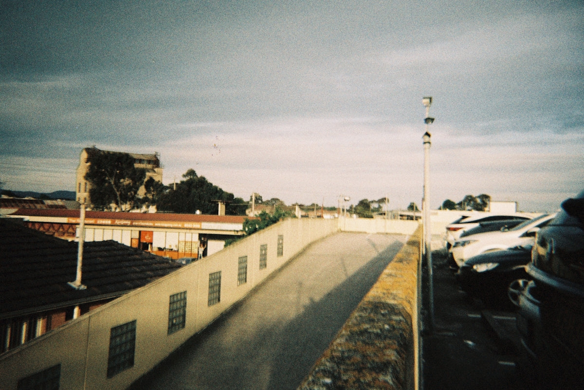 Cars parked near a concrete ramp under cloudy sky