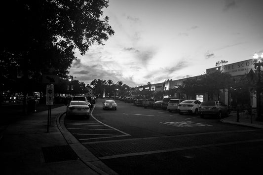 Street scene with parked cars and cloudy sky.