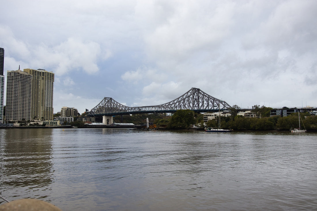 A large bridge spans a wide river under cloudy skies.