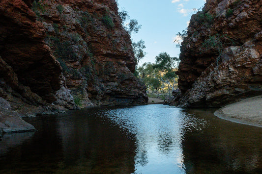 A tranquil pool of water between rocky canyon walls.