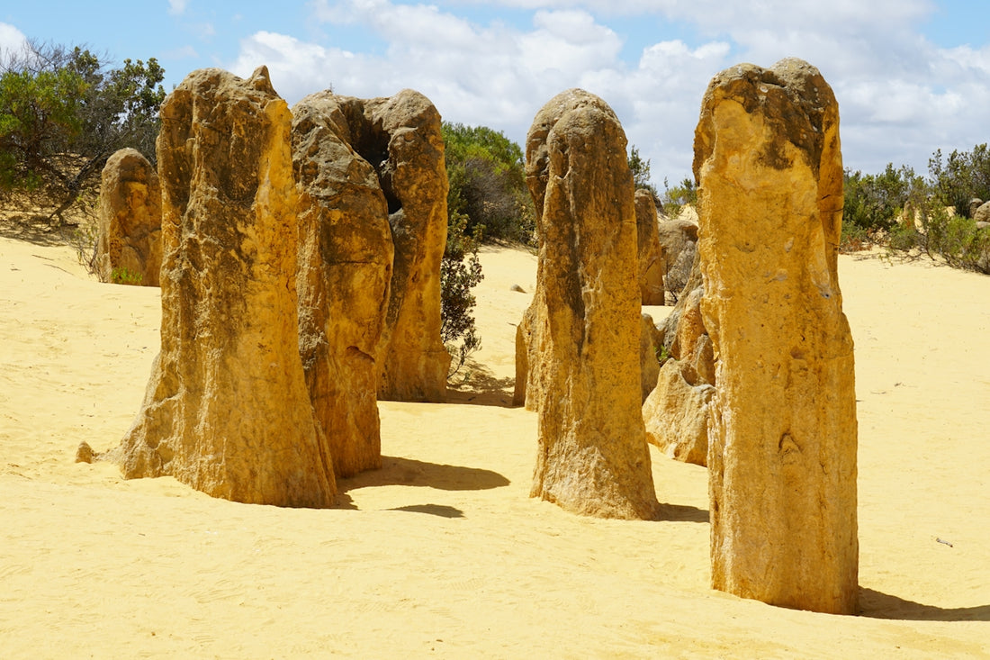 Limestone pinnacles rise from sandy desert landscape.