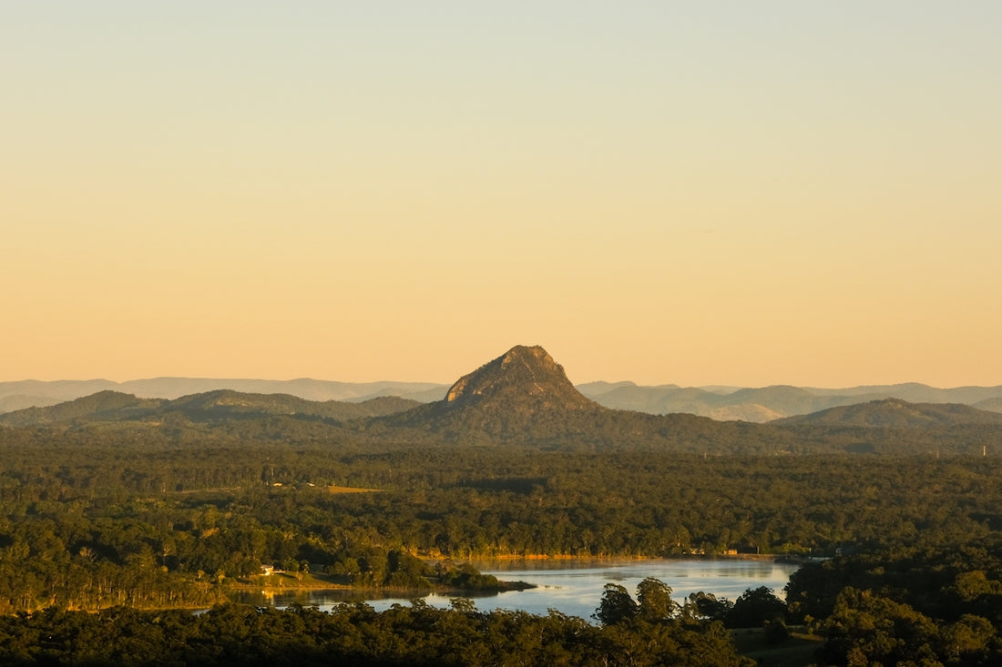 Mountain peak rises above green landscape at sunset