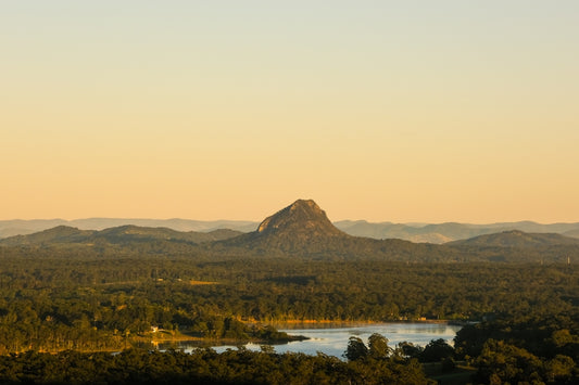 Mountain peak rises above green landscape at sunset