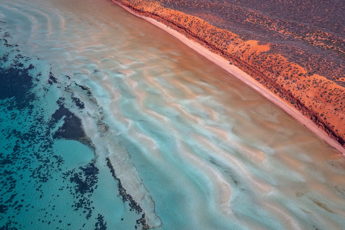 Aerial view of a sandy coastline with shallow turquoise water